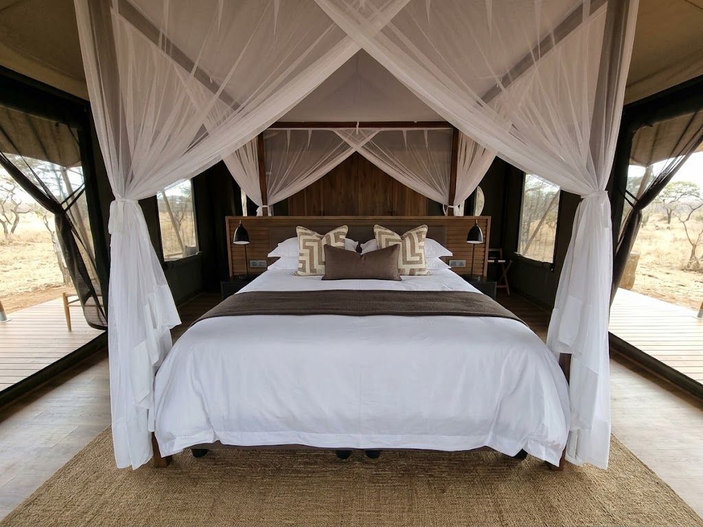 Una cama con dosel, cabecera de madera y vistas al exterior.