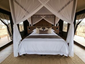 Una cama con dosel, cabecera de madera y vistas al exterior.