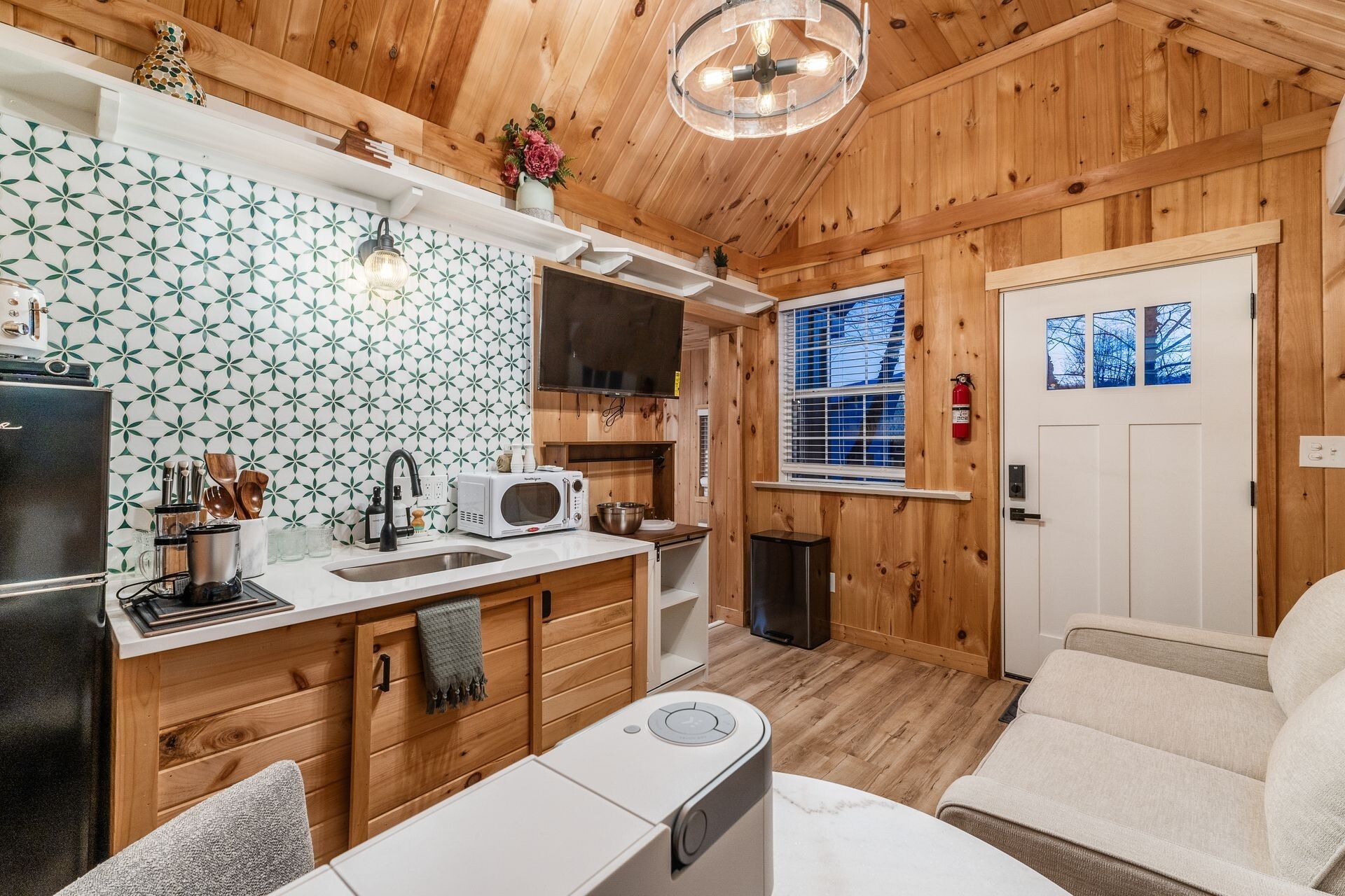 Una cocina compacta con paredes de madera, un microondas, un fregadero y un refrigerador pequeño.