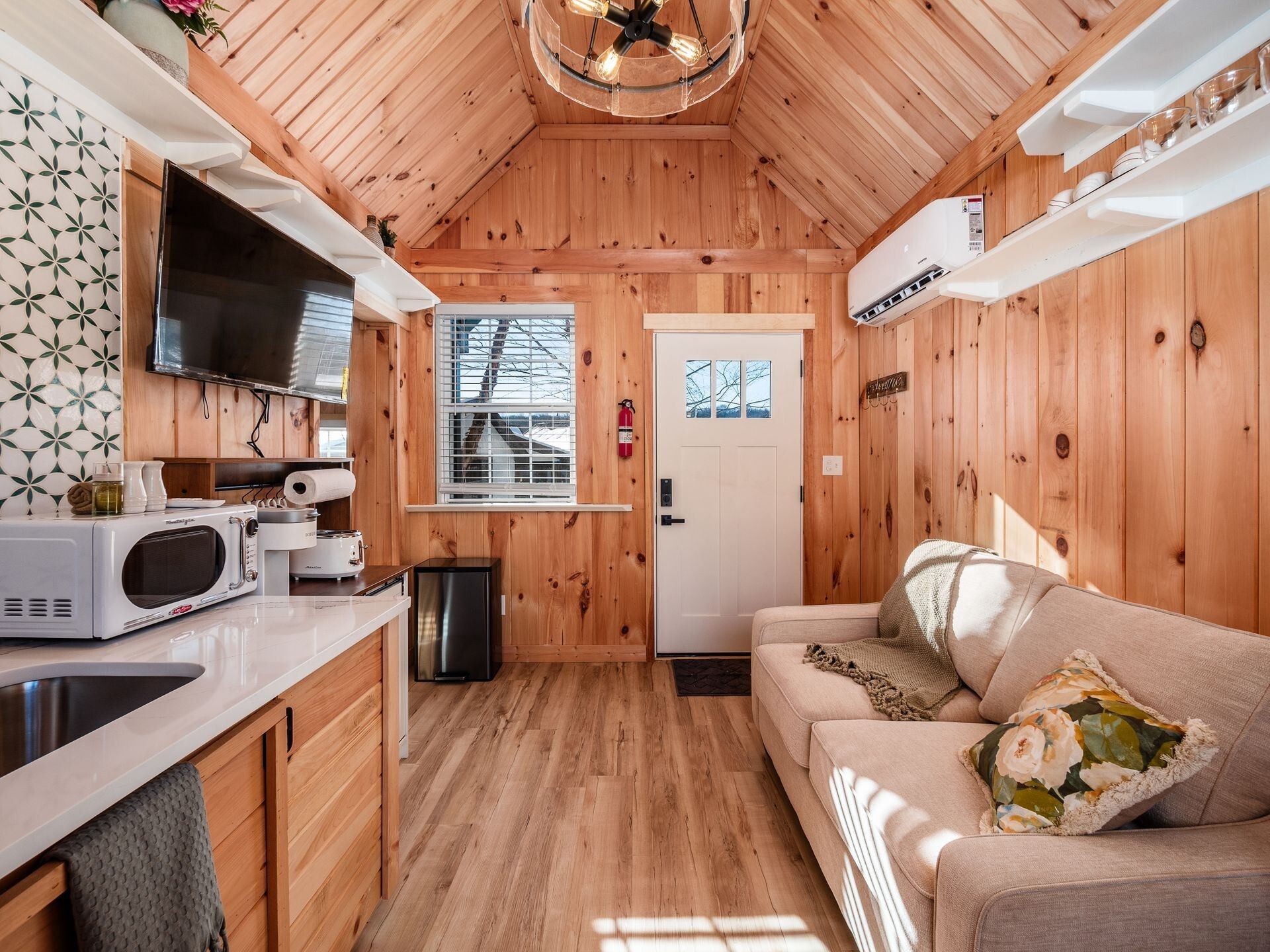 A compact cabin interior with a kitchenette, a sofa, and a television.