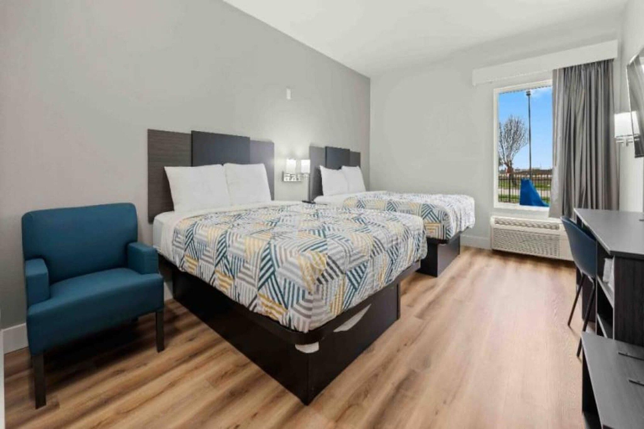 Une chambre d’hôtel avec deux lits, un canapé, un bureau et une vue sur l’extérieur.