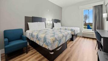 Une chambre d’hôtel avec deux lits, un canapé, un bureau et une vue sur l’extérieur.