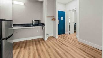 A modern kitchen with a microwave, a refrigerator, and a wooden floor.