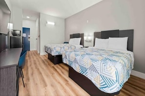 Una habitación de hotel con dos camas, un escritorio y una televisión.