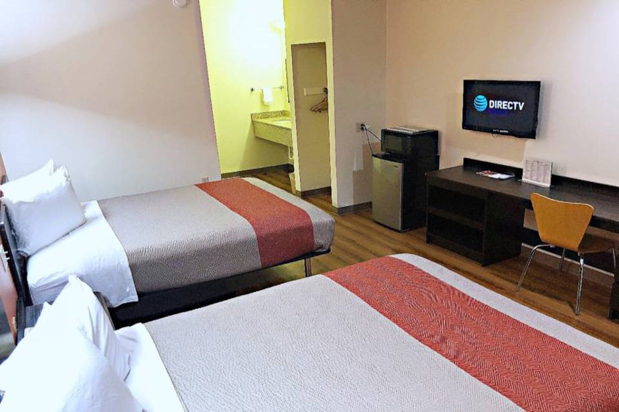 Hotellihuone, jossa on kaksi sänkyä, työpöytä, televisio ja pieni keittonurkkaus.