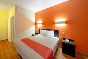 Una habitación de hotel con una cama, mesitas de noche y una puerta.