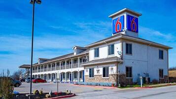 A motel with a prominent '6' sign, multiple rooms, and a parking lot.