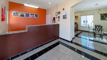 A hotel lobby with a reception desk, a tiled floor, and a view of the outside.