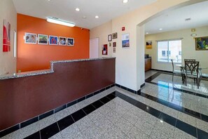 Un vestíbulo de hotel con una recepción, suelo de baldosas y vistas al exterior.