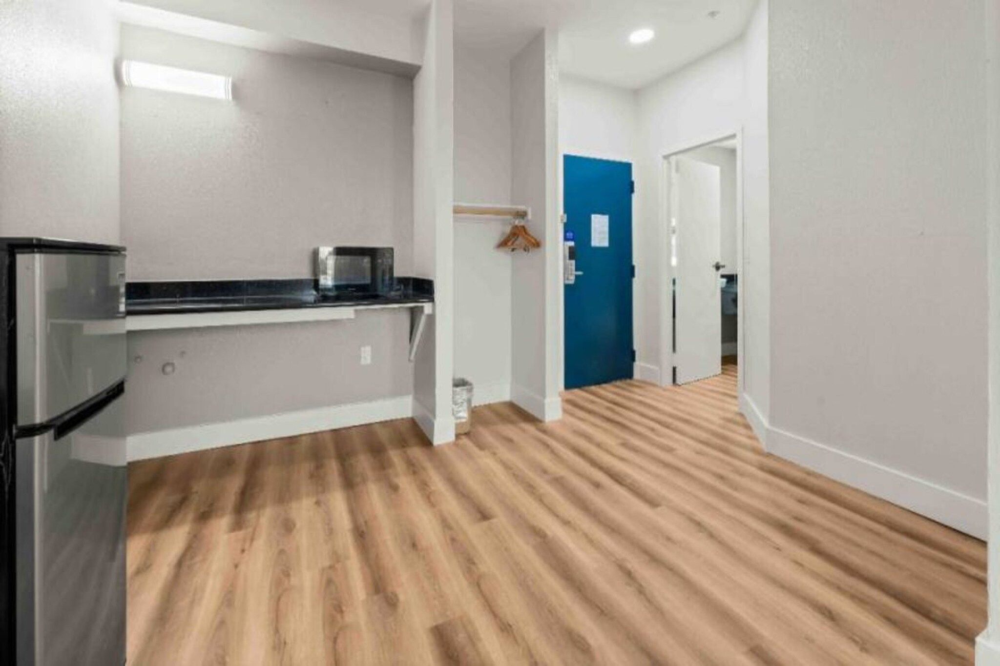 A modern kitchen with a microwave, a refrigerator, and a wooden floor.
