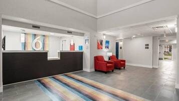 A reception area with a black reception desk, red chairs, and a colorful striped carpet.