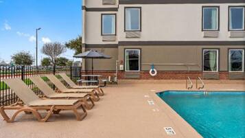 A poolside area with lounge chairs and a pool.