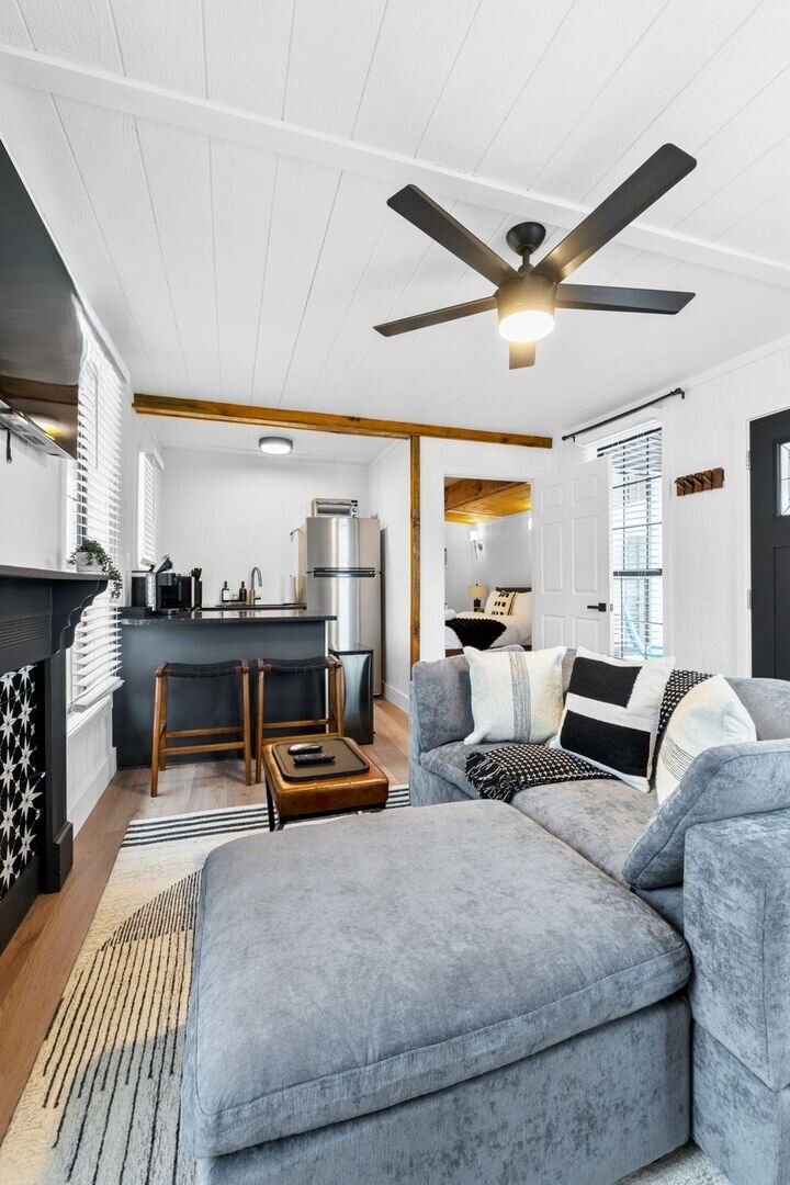 A modern living room with a grey sofa, a coffee table, and a ceiling fan.