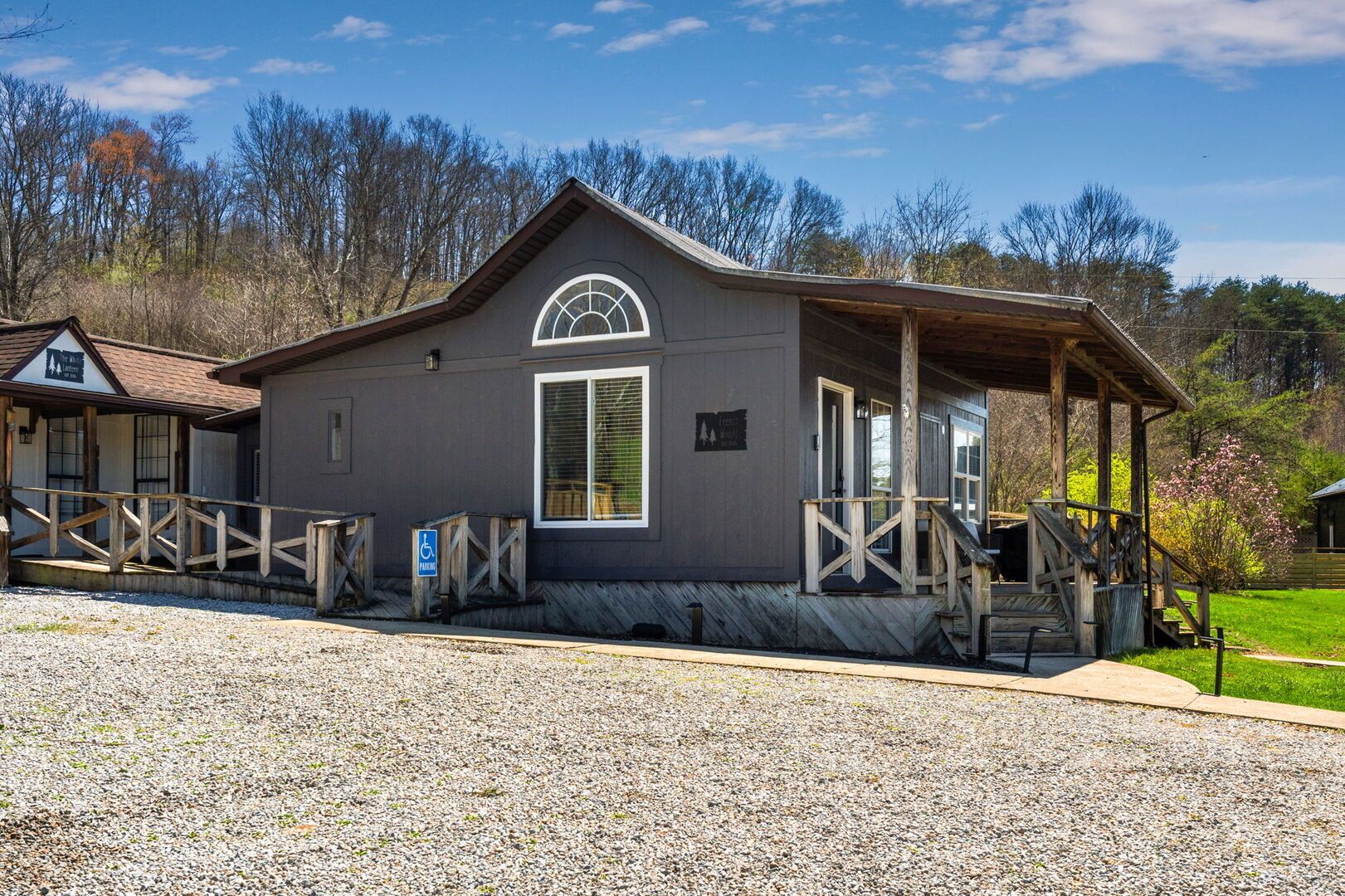 A rustic lodge with a covered porch, a wheelchair-accessible entrance, and a gravel driveway.