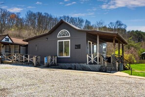 Un chalet rustique doté d’un porche couvert, d’une entrée accessible aux personnes à mobilité réduite et d’une allée en gravier.