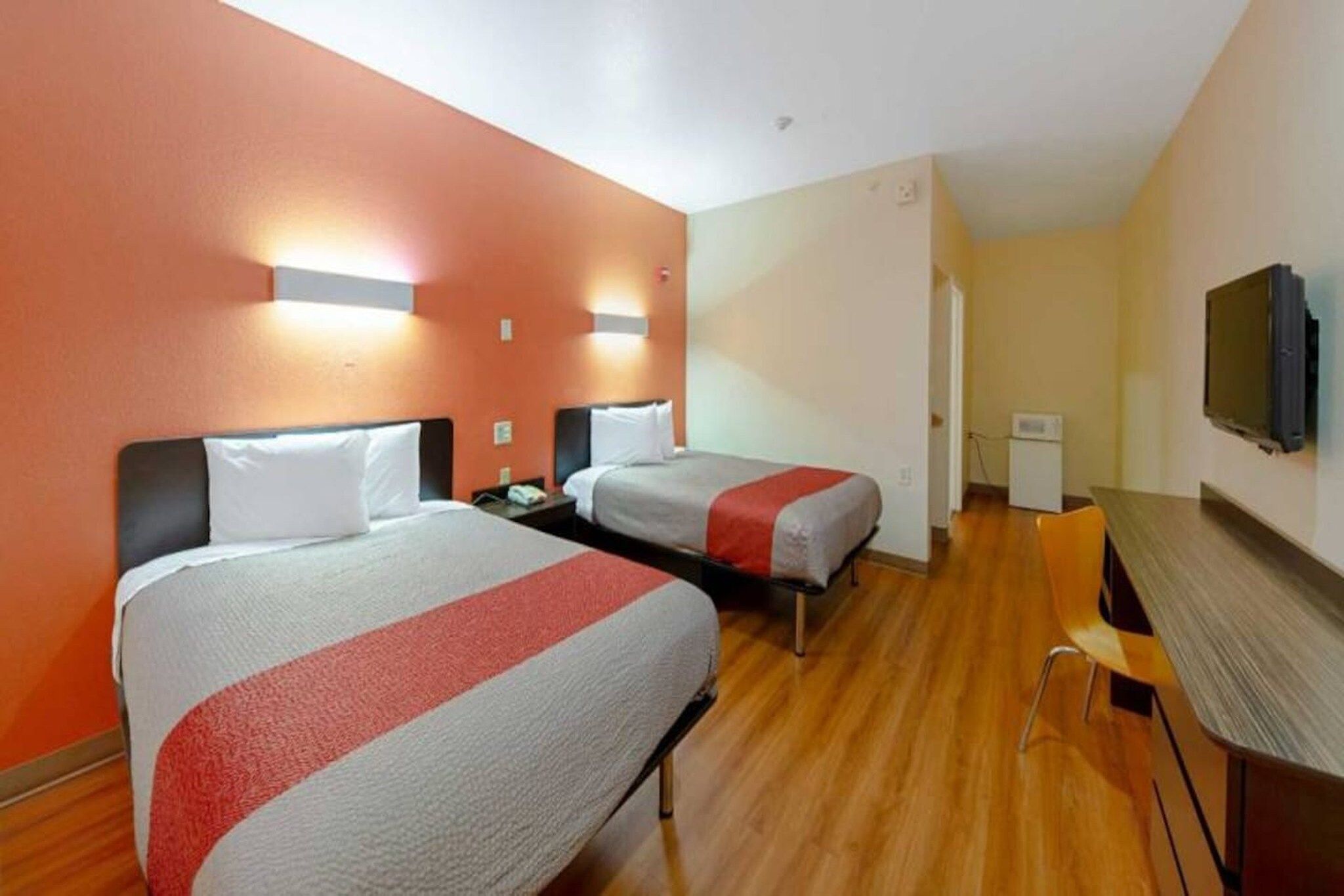 A hotel room with two beds, a desk, and a television.
