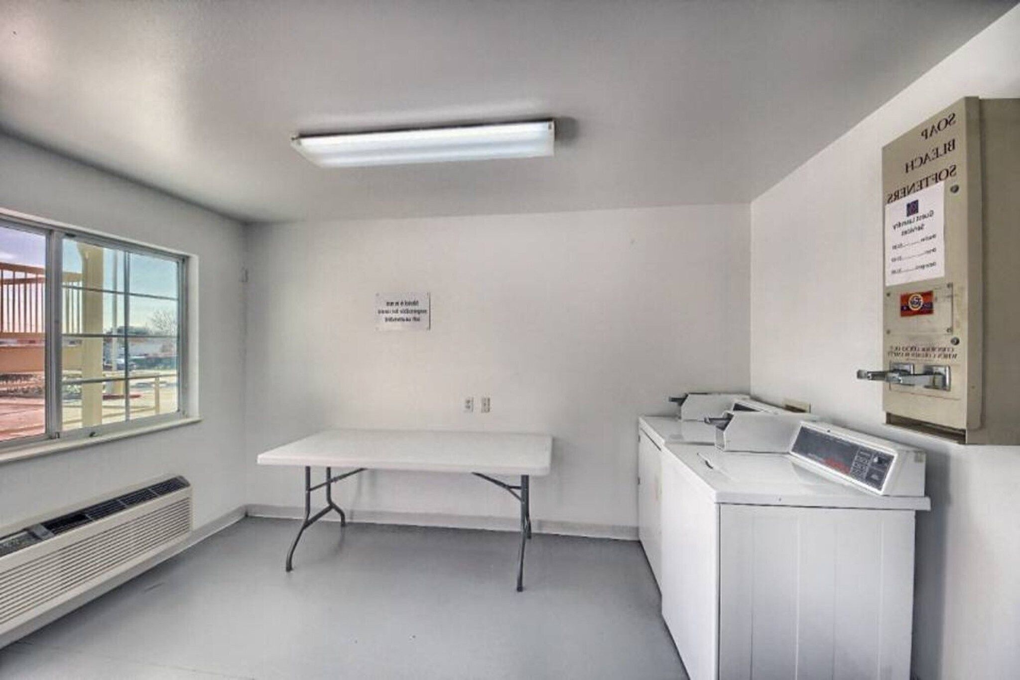 A room with a table, a washing machine, a heater, and a window with a view.