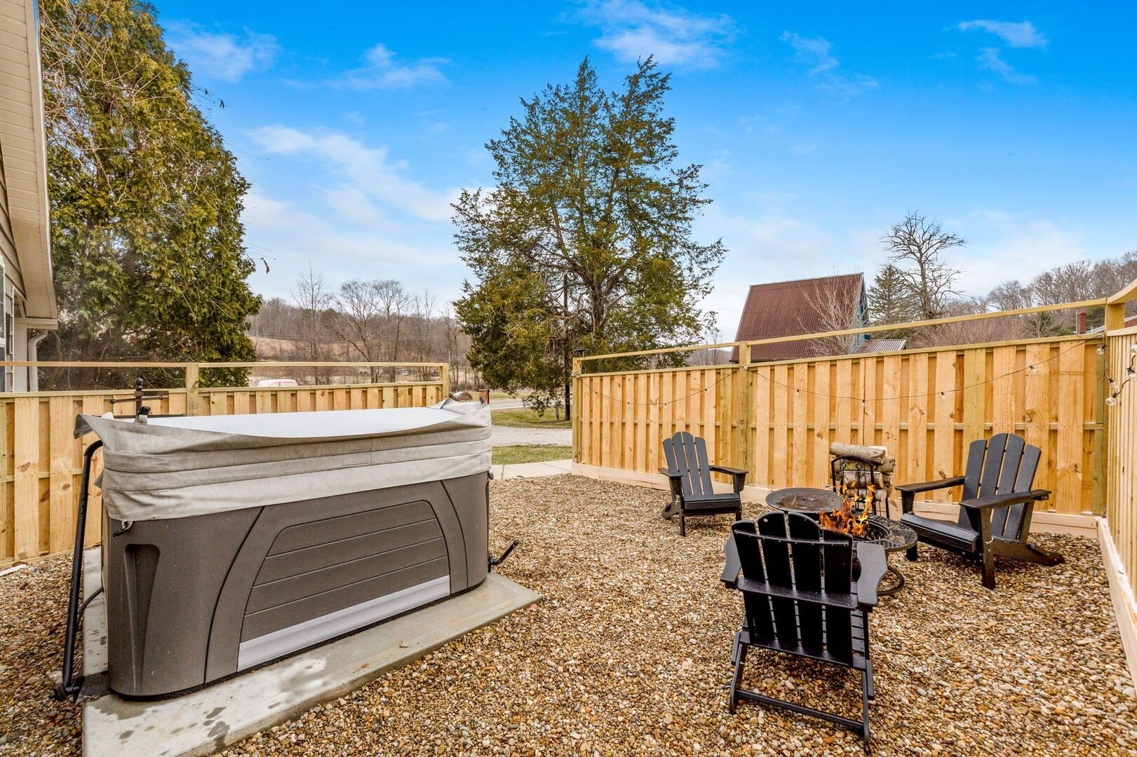 Un patio trasero con jacuzzi, mobiliario exterior y cerca de madera.