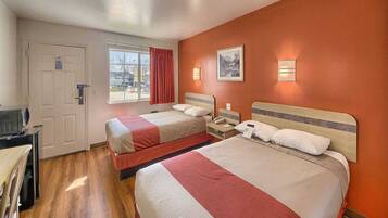 A hotel room with two beds, a desk, a chair, a window with curtains, and a door.