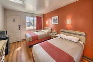 Una habitación de hotel con dos camas, un escritorio, una silla, una ventana con cortinas y una puerta.
