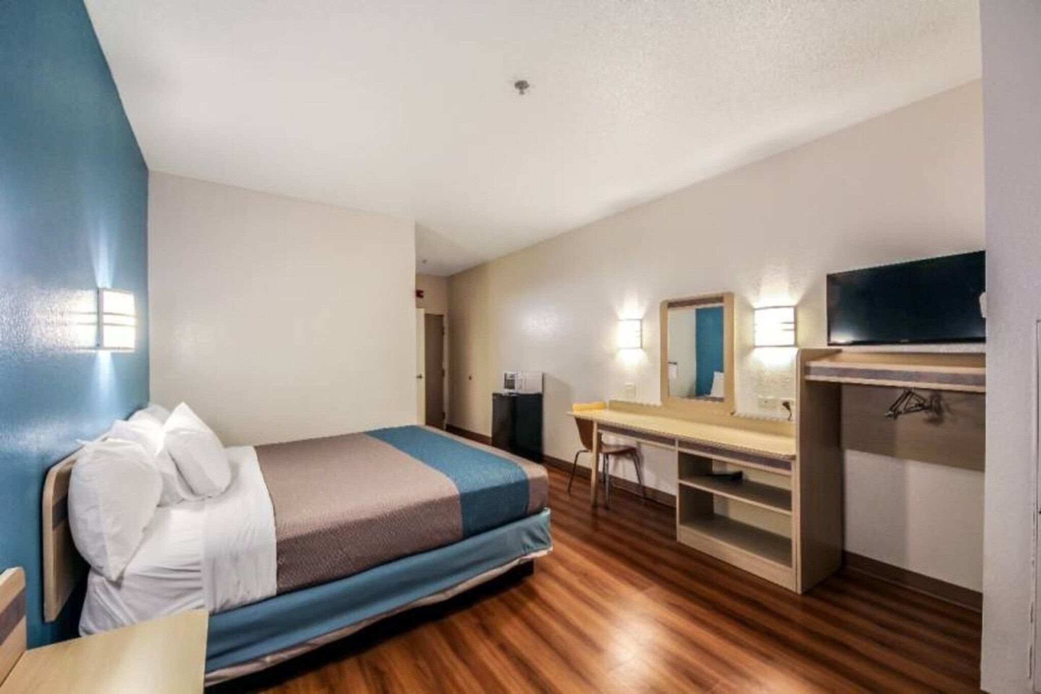 A hotel room with a bed, desk, and a television.