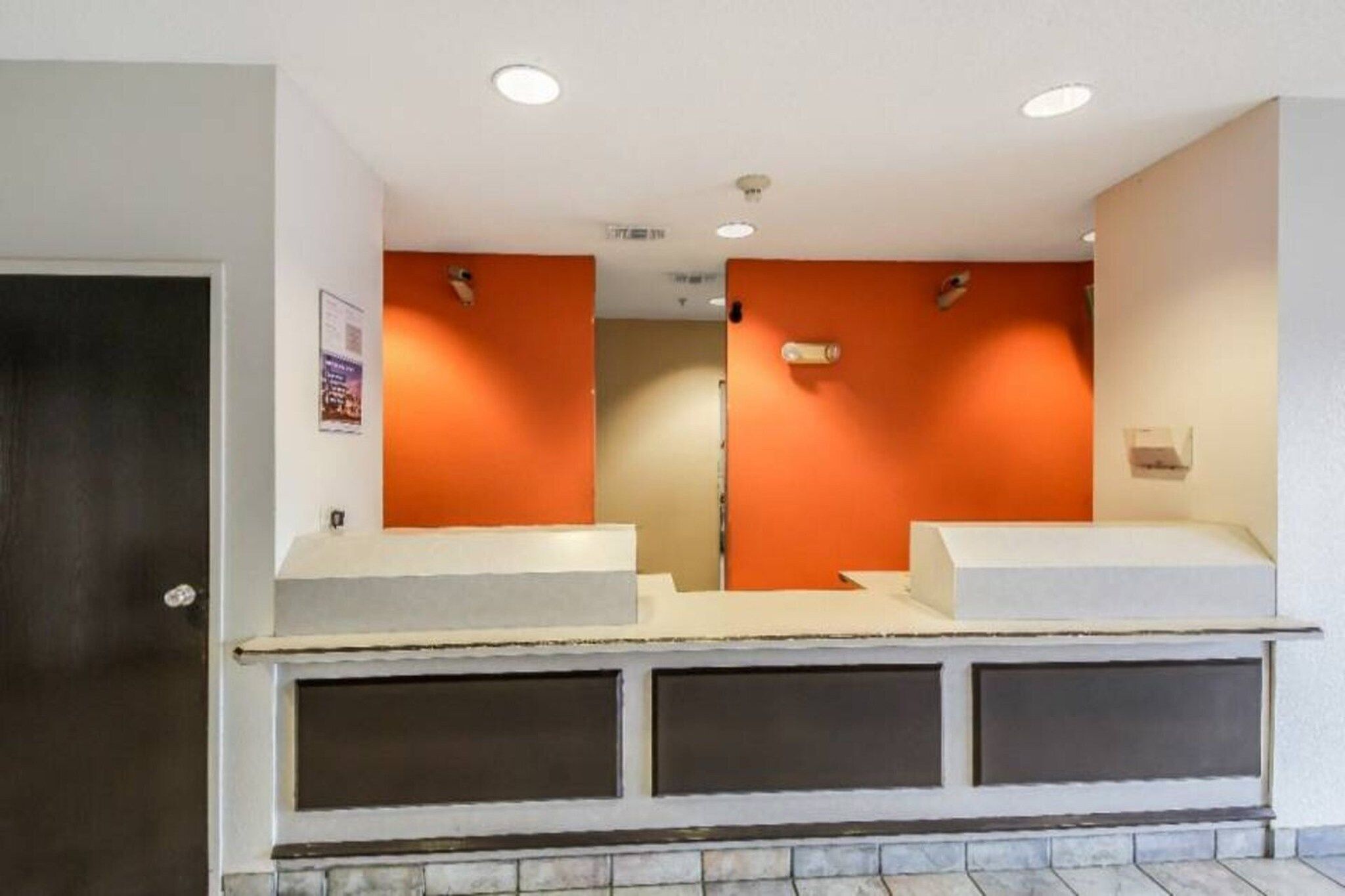 A reception area with a counter, two sinks, and a door.