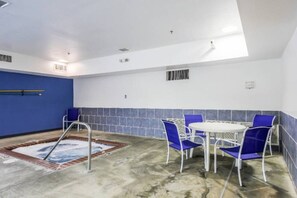 A swimming pool area with a hot tub, blue chairs, and a table. - 1 King Bed | Mobil Access Tub Nsmk Micfridg (New Braunfels)