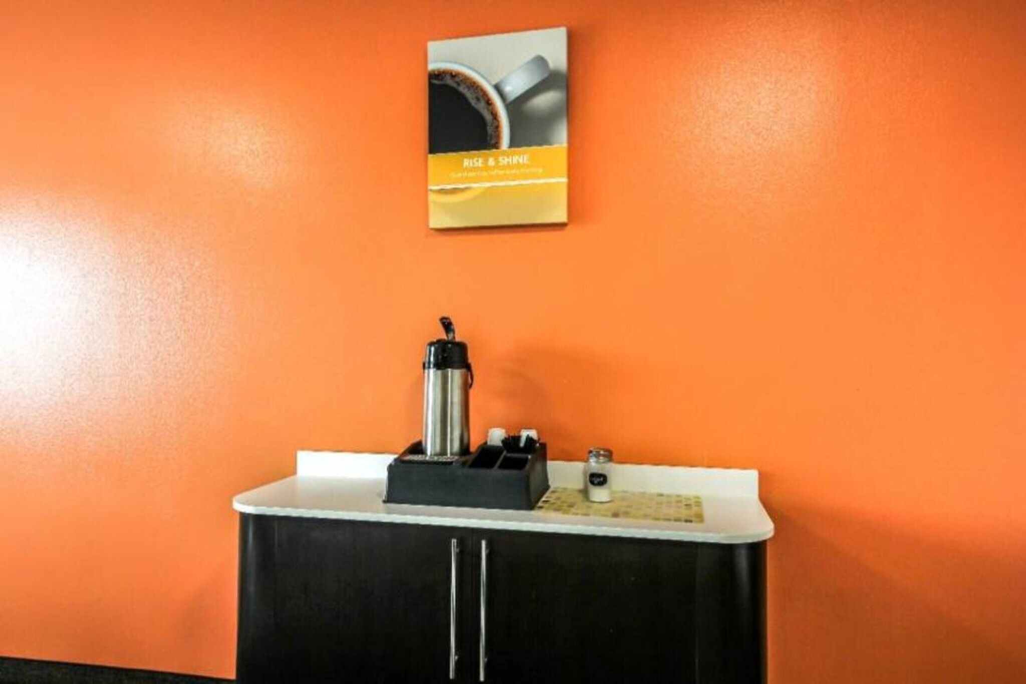 Een kleine kitchenette met een koffieapparaat, een waterkoker en een zoutvaatje op het aanrecht.