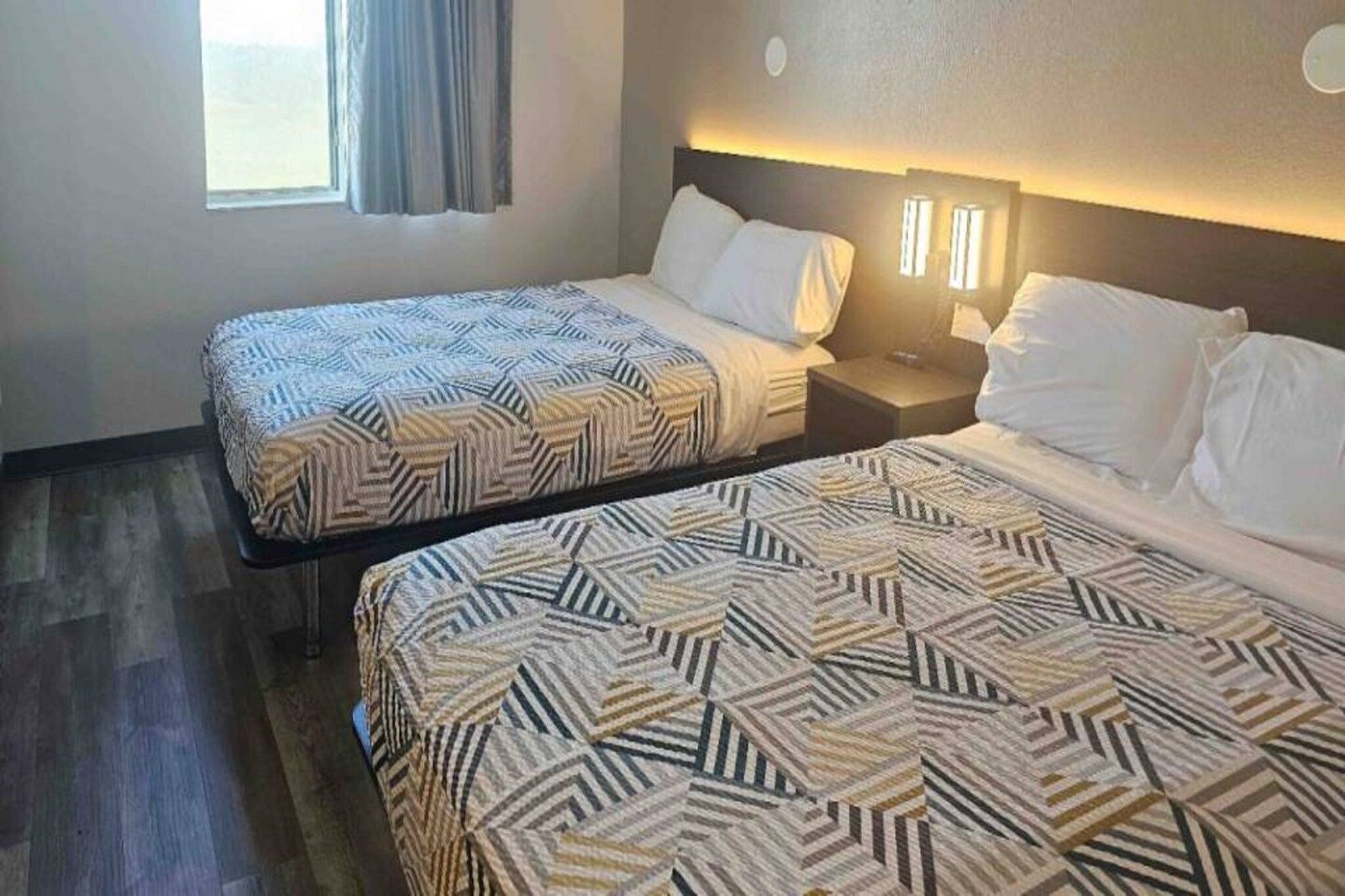 Dos camas individuales con ropa de cama estampada en una habitación de hotel.