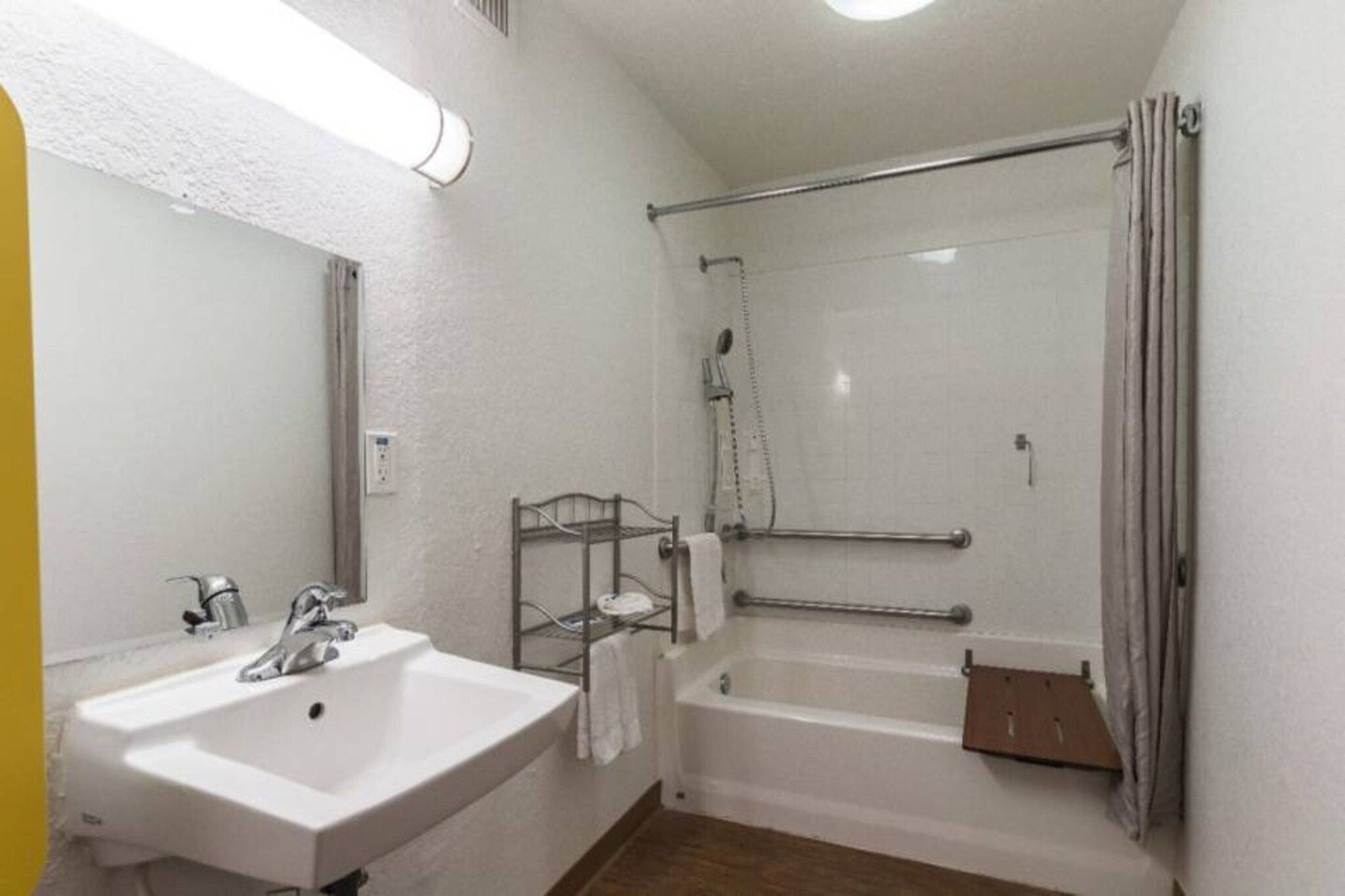 A bathroom with a sink, bathtub, shower, and towel rack.