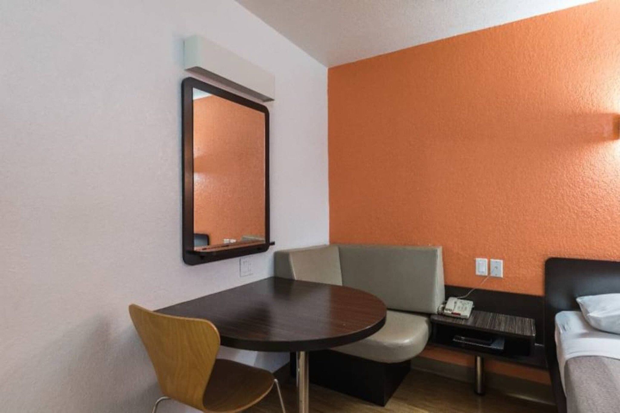 A hotel room with a round table, a single chair, a sofa, and a bed.
