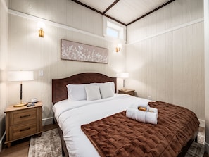 Una habitación de hotel con una cama grande, dos mesitas de noche, un ventanal y una obra de arte colgada en la pared.