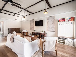 Amplia sala de estar con techo alto, chimenea, televisor y estantería de juegos.