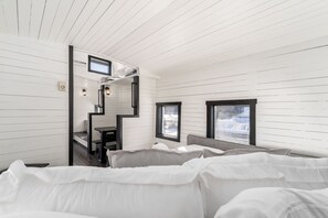 Un intérieur moderne avec un escalier, un lit et une fenêtre donnant sur l’extérieur.