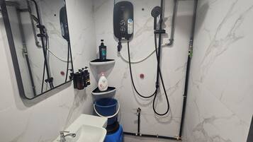 Une petite salle de bain avec un lavabo blanc, un miroir, une douche et des toilettes.