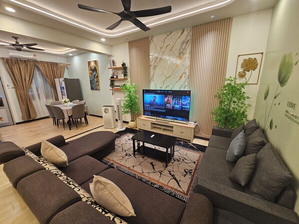 A modern living room with a sofa, TV, and a dining area with a table and chairs.