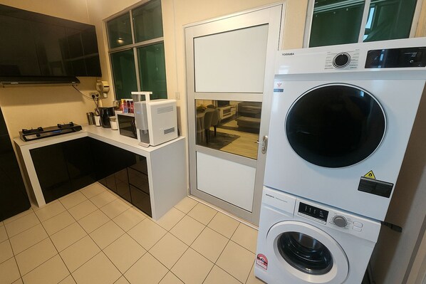 Una cocina compacta equipada con microondas, tostadora, lavadora y secadora apiladas.