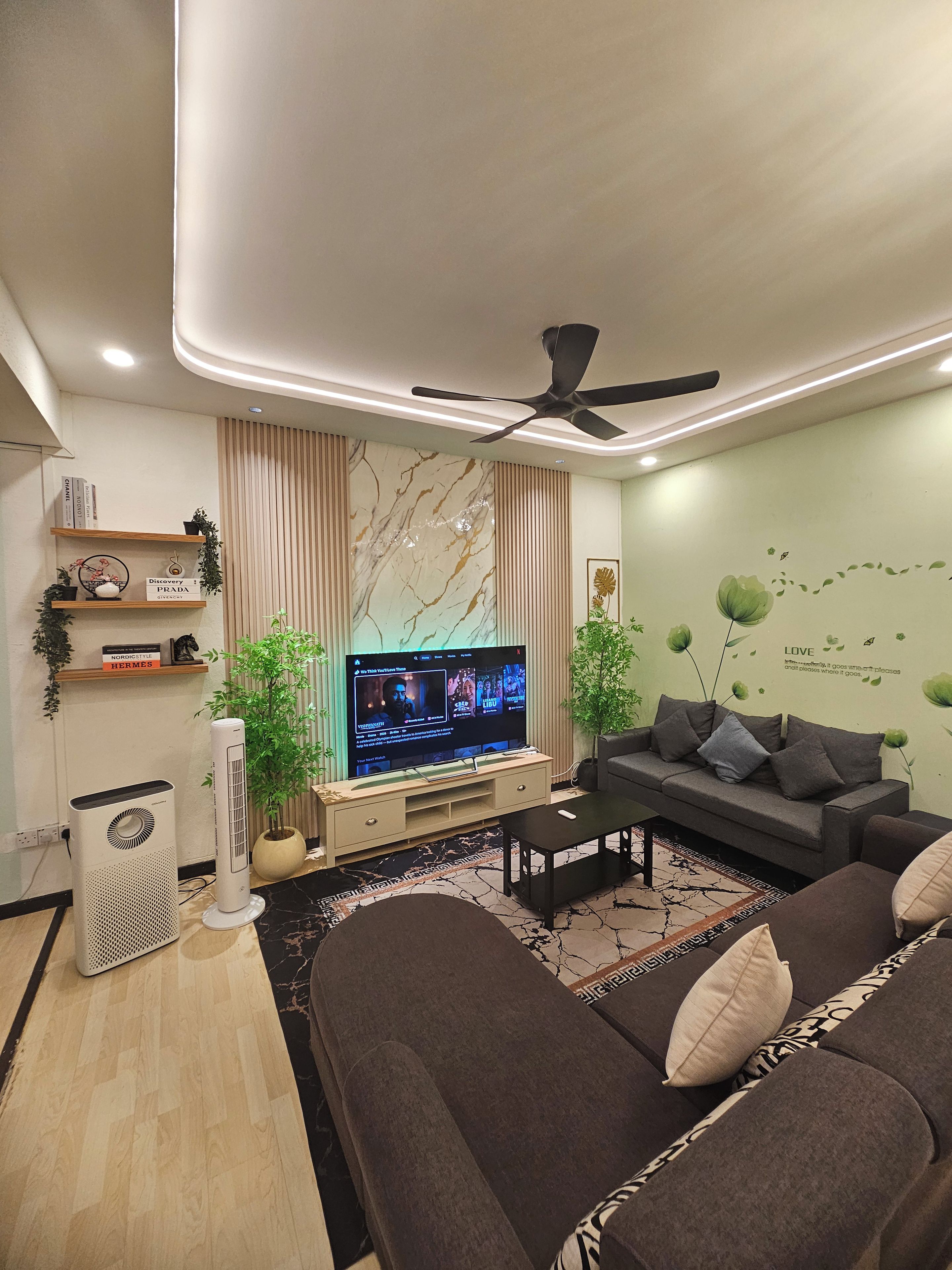 Un salon moderne doté d’un téléviseur à écran plat, d’un ventilateur de plafond, d’un canapé et d’une table basse.
