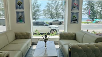 Een kamer met twee beige banken, een marmeren salontafel en uitzicht op de zee door grote ramen.