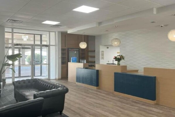 A reception area with a reception desk, a seating area with a sofa, and a large window providing natural light.