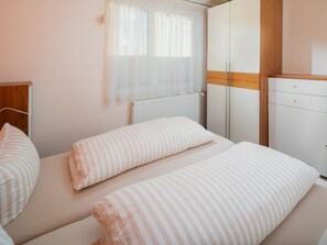 Ein Schlafzimmer mit zwei Betten, einem Schrank und einem Fenster mit Vorhängen.