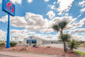 Un motel avec une grande enseigne bleue indiquant la présence d’une connexion Wi-Fi, une entrée accueillante et un parking.