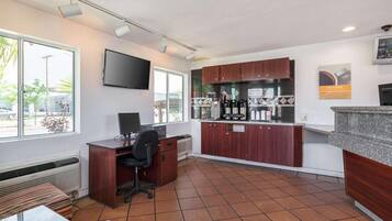 Espacio de oficina compacto con escritorio, silla y una pequeña área de cocina.