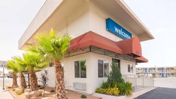 Un edificio con un letrero que dice 'Welcome', palmeras y una señal de límite de velocidad.