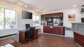 Espacio de oficina compacto con escritorio, silla y una pequeña área de cocina.