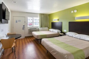 Quarto de hotel com duas camas, uma escrivaninha, uma cadeira e uma televisão.