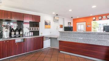 A modern kitchen with a coffee station, a counter, and a tiled floor.