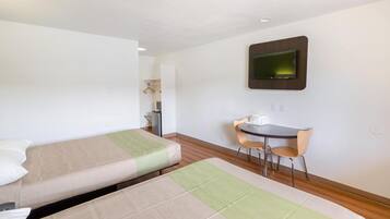 A hotel room with two single beds, a desk with a chair, and a television mounted on the wall.