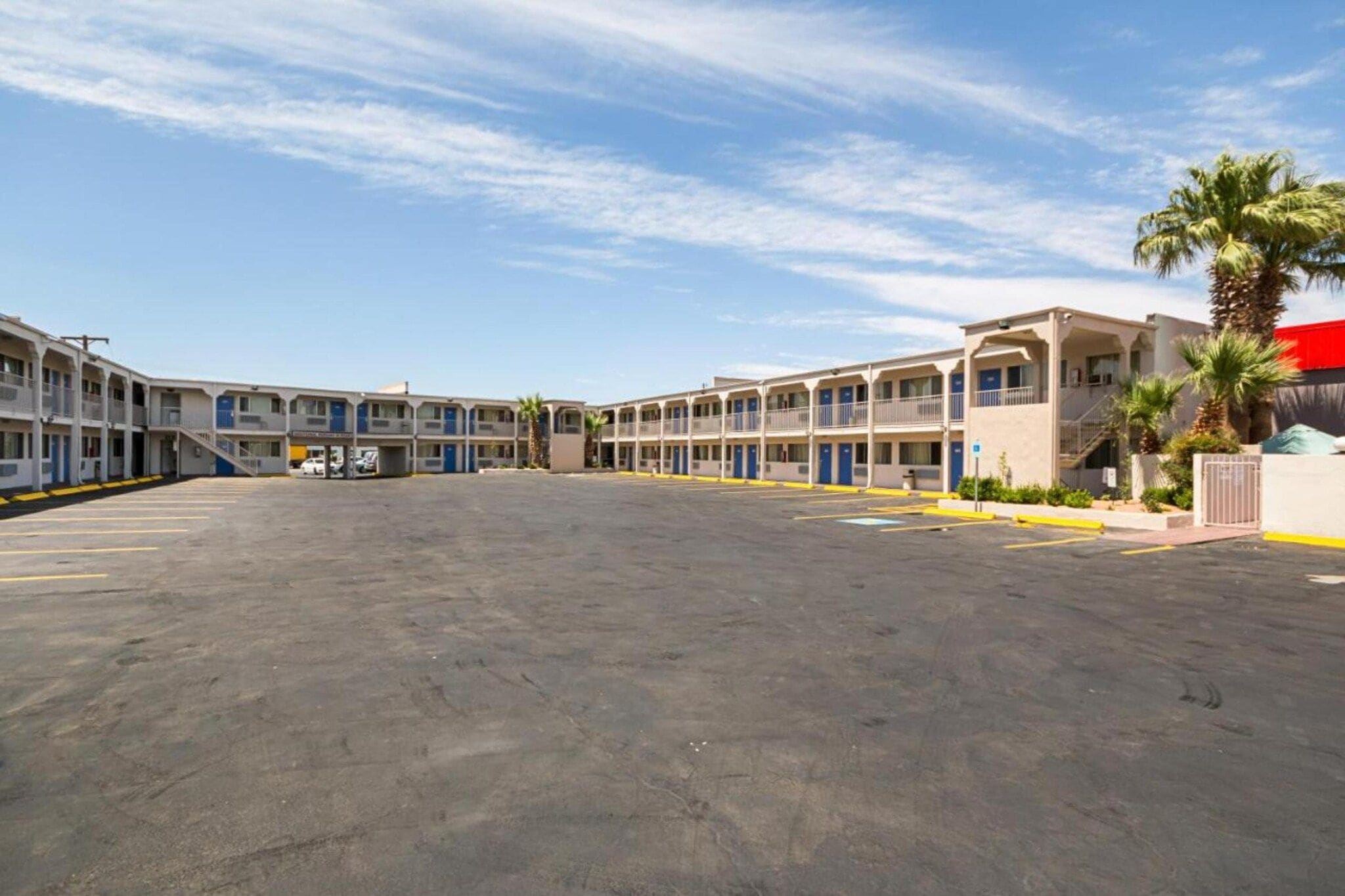 A motel with multiple rooms, a parking lot, and a clear sky.