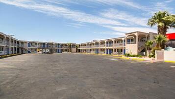 A motel with multiple rooms, a parking lot, and a clear sky.